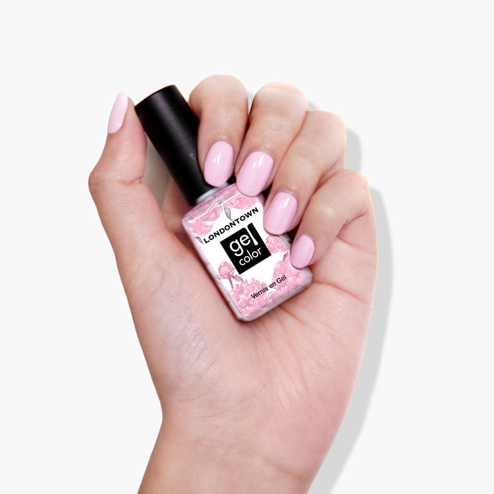 A hand with pink, manicured nails holds a bottle of LONDONTOWN cruelty-free gel nail polish in the shade Afternoon Tea, featuring a floral design.