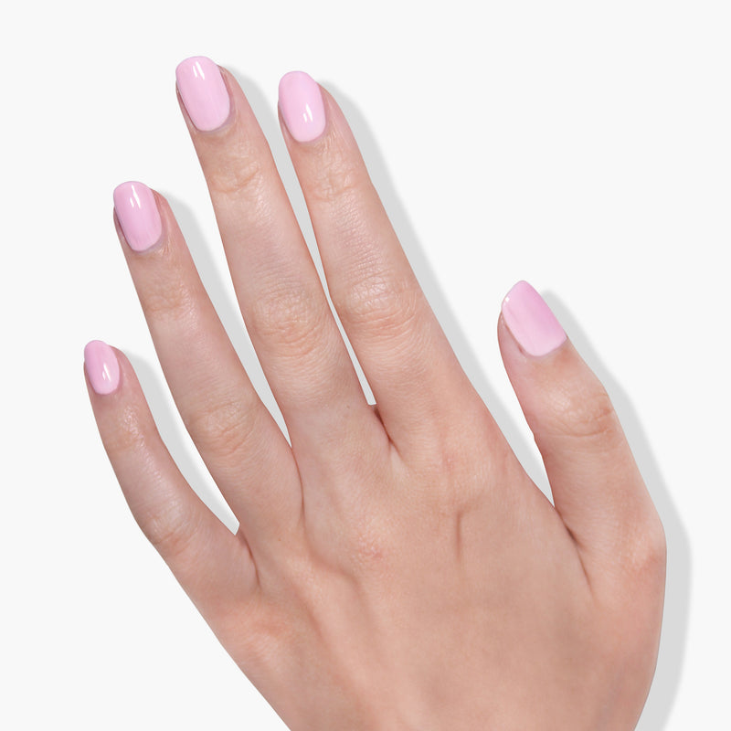 A close-up of a hand with neatly manicured nails painted in the light pink crème color of "Afternoon Tea" by LONDONTOWN on a white background, showcasing vegan and cruelty-free nail polish.