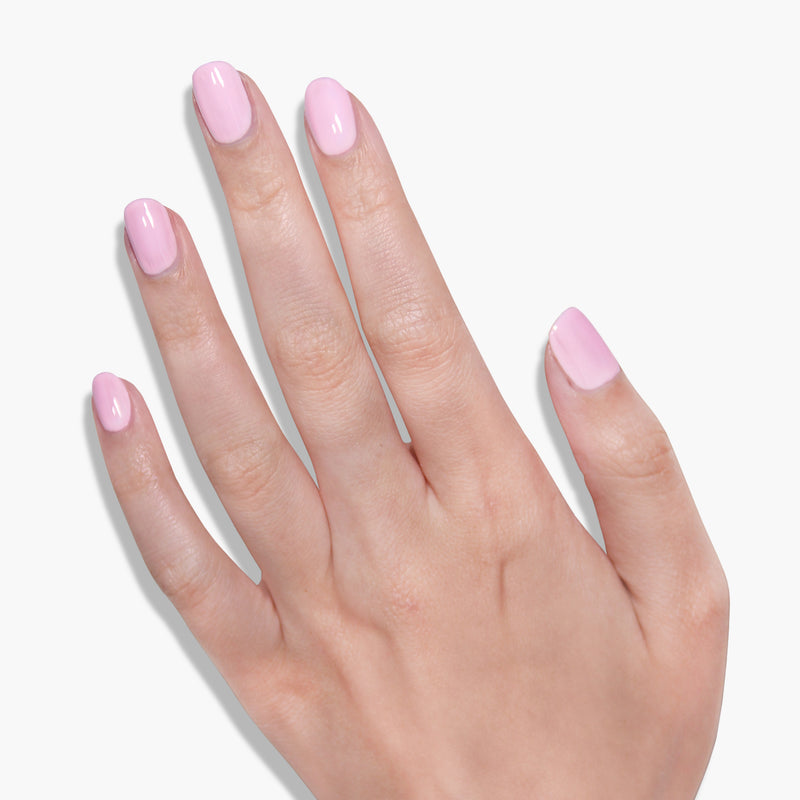 A close-up of a hand with neatly manicured nails painted in LONDONTOWN's Afternoon Tea light pink crème polish against a white background, creating a warm and cozy feel.