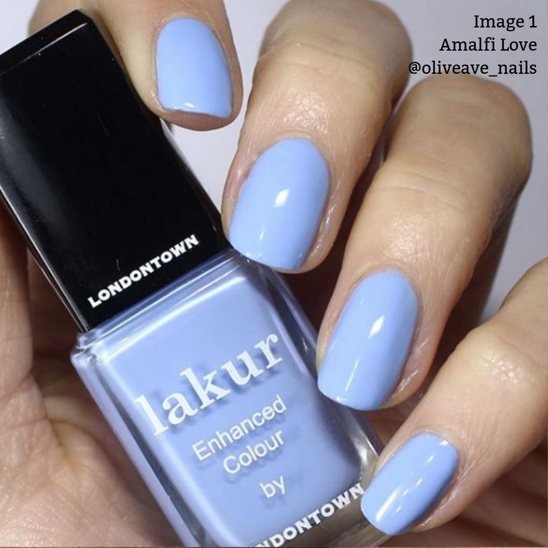 Close-up of a hand with nails painted in LONDONTOWN's Lakur nail polish, shade "Amalfi Love," a cool blue tone. The vegan, cruelty-free bottle is held between the fingers. Text in the image reads "@oliveave_nails.