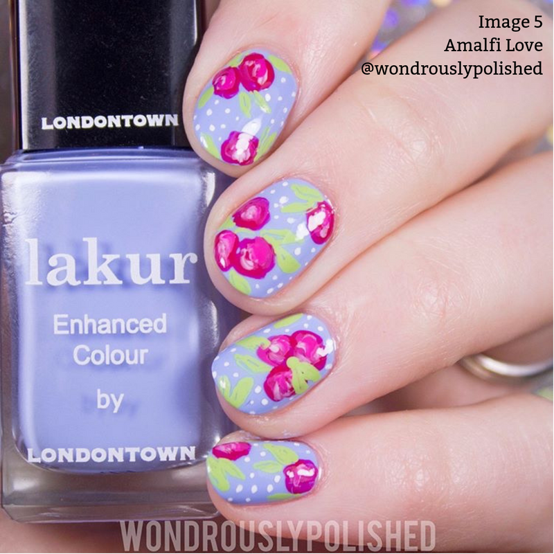 A hand adorned with intricate floral nail art in pink, green, and white on a lavender base is seen beside a bottle of LONDONTOWN lakur nail polish labeled "Amalfi Love," featuring a cool blue tone and boasting a 16+ Free formula that is vegan and cruelty-free.