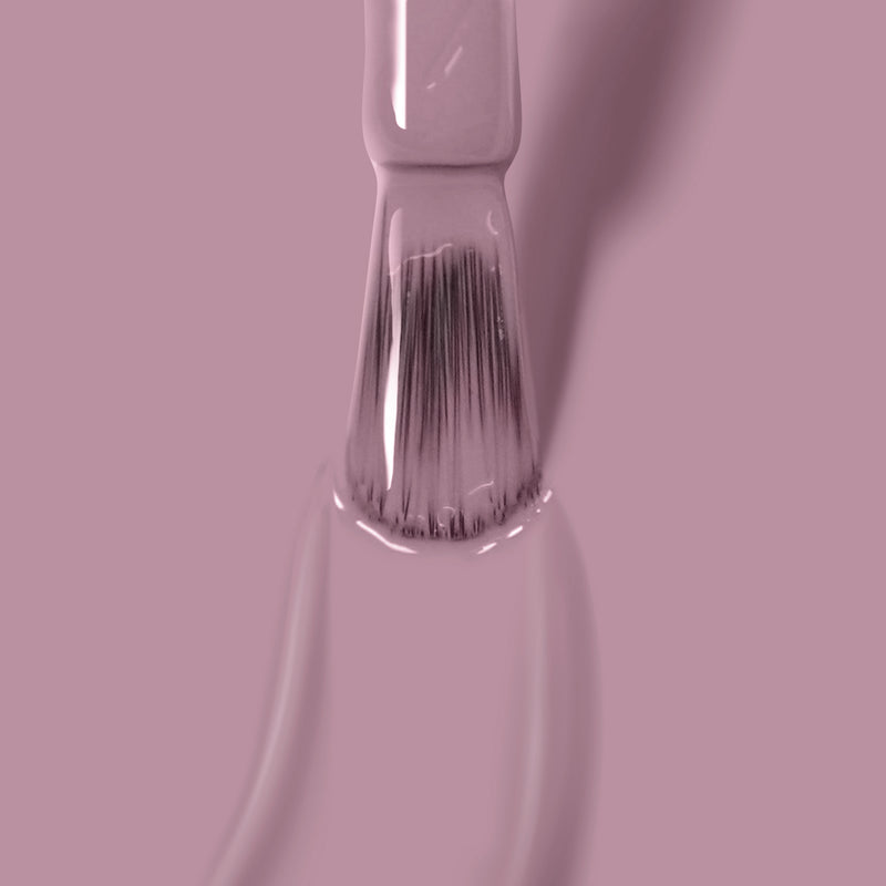 Close-up of a paintbrush coated in LONDONTOWN's Bell Flower vegan paint, with the bristles partially submerged in the paint.