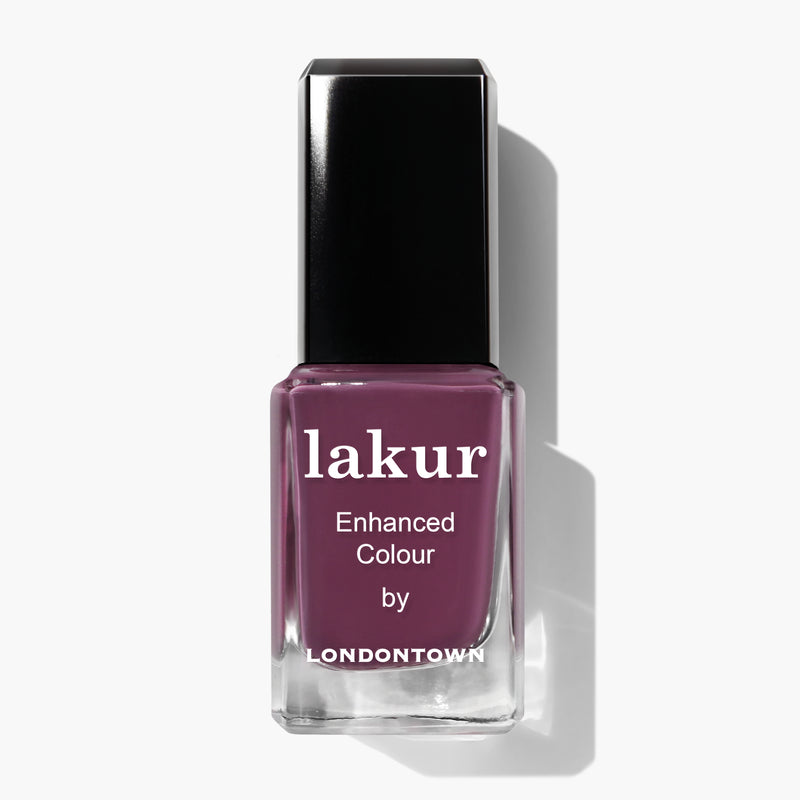 A bottle of LONDONTOWN's Lakur Enhanced Colour nail polish in the "Best Year Ever" shade, featuring a dreamy dark purple hue and a black cap, placed on a white background.
