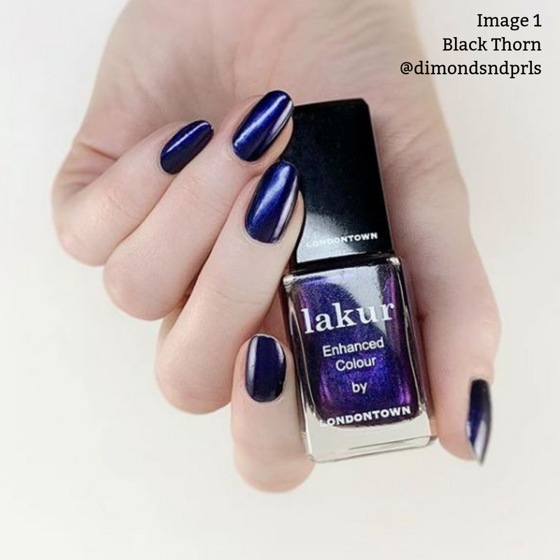 A hand with dark blue metallic nail polish holds a bottle of LONDONTOWN's Lakur Enhanced Colour nail polish in the shade "Black Thorn." This moody midnight purple is 16+ Free and vegan cruelty-free. Text reads "Image 1 Black Thorn @dimondsndprls.