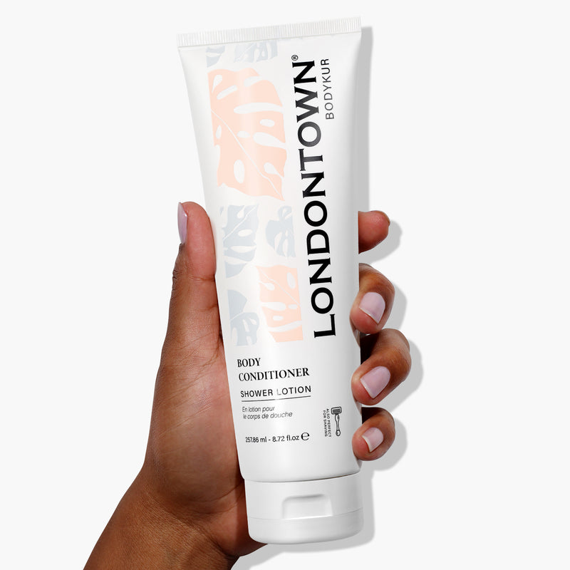 A hand holding a white tube of LONDONTOWN Nourishing Body Conditioner against a plain white background, promising smoother skin.