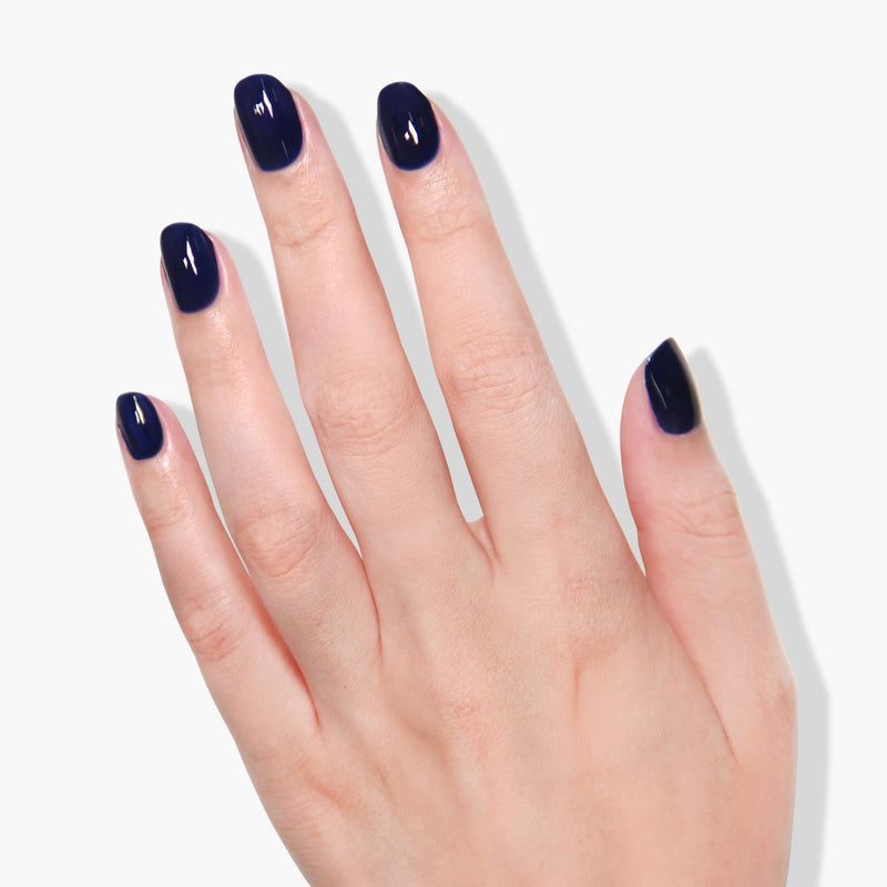 A hand with fingers spread, showcasing nails painted in LONDONTOWN's vibrant Buckingham Blue against a pristine white background.