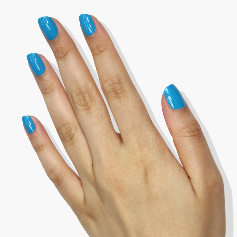 A hand with manicured nails painted in LONDONTOWN's Cabana Boy, a glossy neon blue color, against a white background.