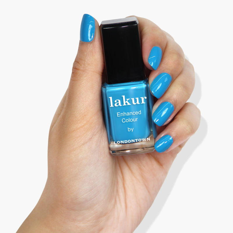 A hand with neon blue-painted nails holds a bottle of "Cabana Boy" nail polish by LONDONTOWN.