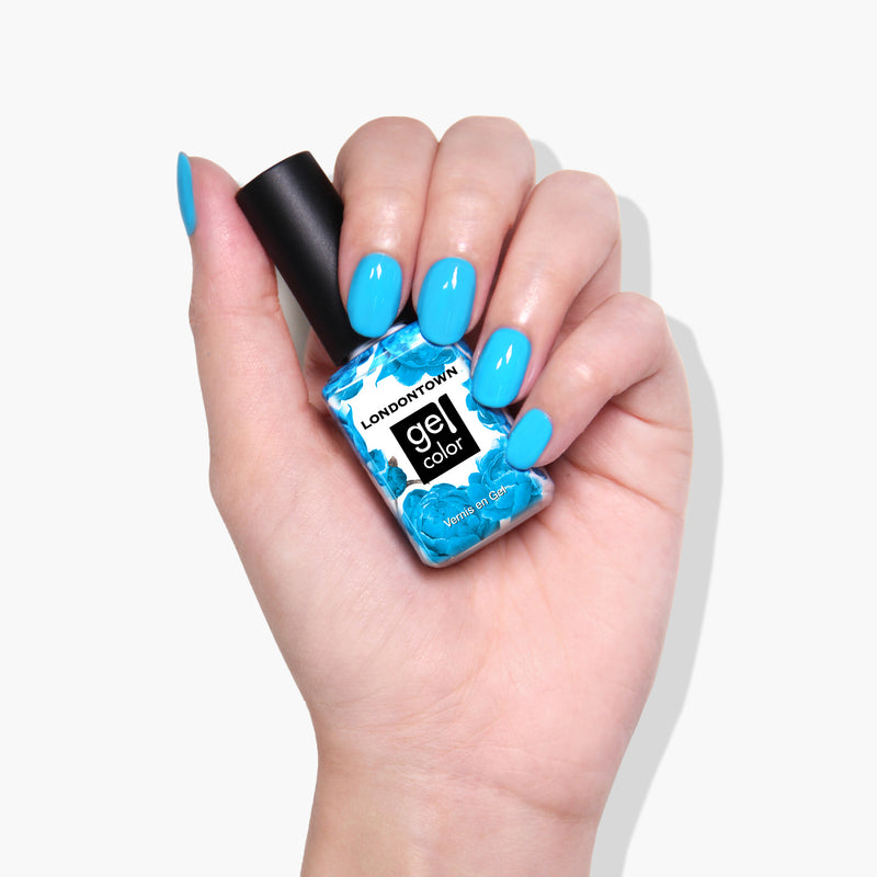 A hand with neon blue nail polish holds a bottle of LONDONTOWN Cabana Boy Gel Color in vibrant, extended wear & shine blue.