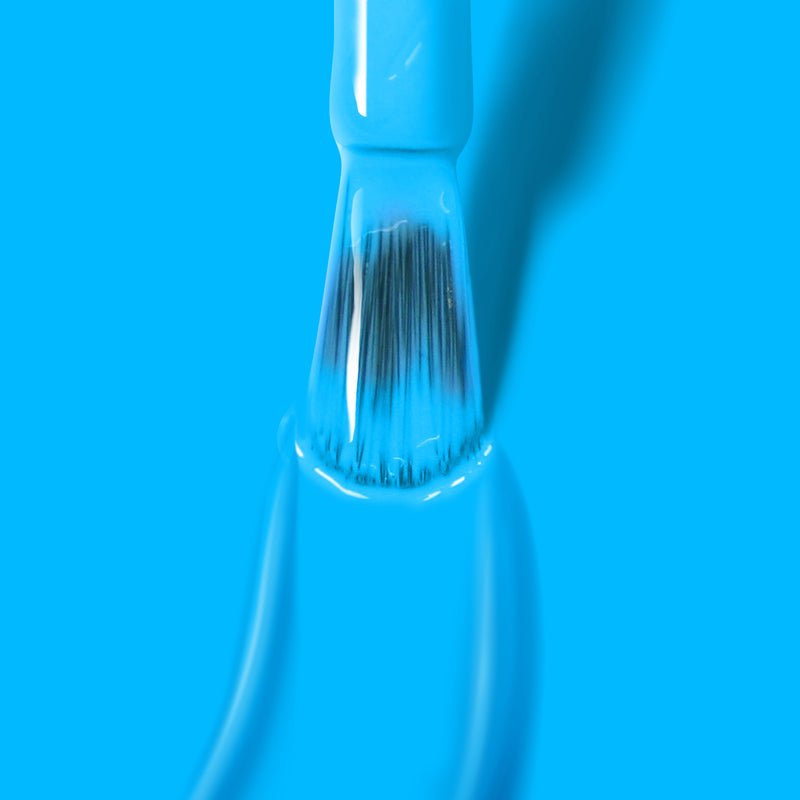 A close-up image of a brush coated with LONDONTOWN's Cabana Boy, a neon blue paint, against a solid blue background, capturing the vibrant hue ready for extended wear & shine under UV/LED light.