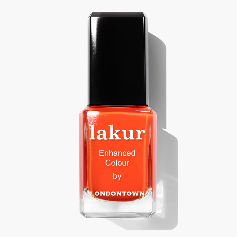 A bottle of Camden Chic by LONDONTOWN features a citrusy orange crème nail polish with a black cap. This vegan, cruelty-free formula is also 16+ Free, ensuring your manicure is vibrant and safe.