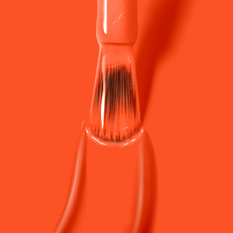 Close-up of a paintbrush coated with Camden Chic by LONDONTOWN against an orange background.