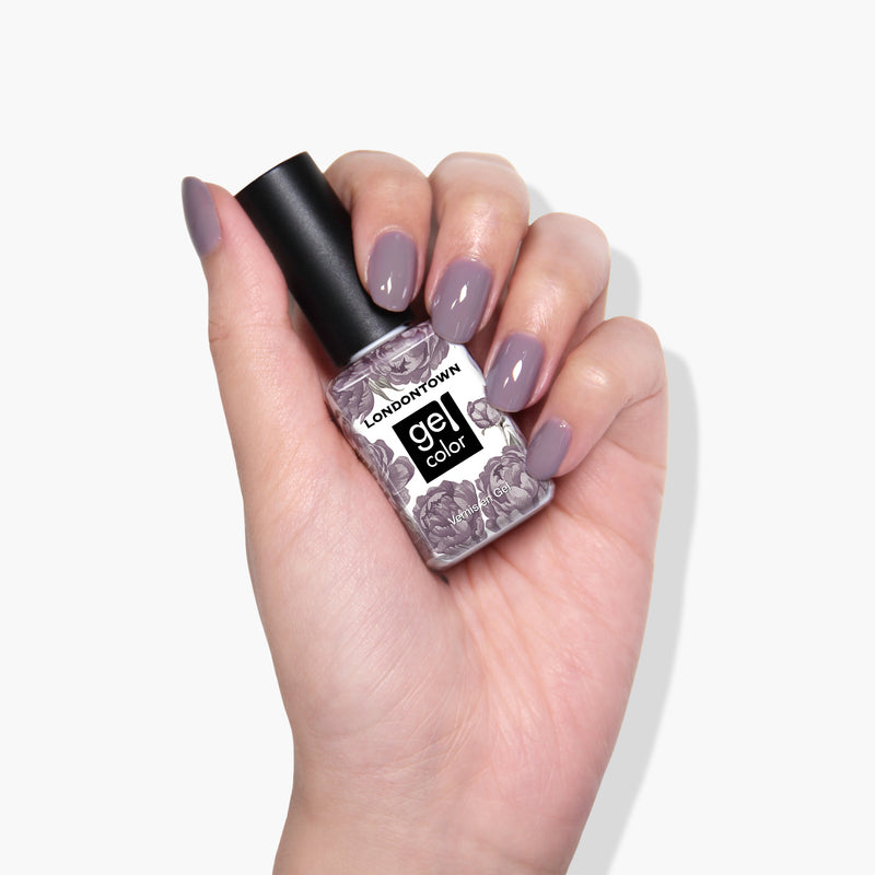 A hand with polished nails holds a bottle of LONDONTOWN gel nail color in Cashmere, a rich plum shade renowned for its superior one-coat coverage.