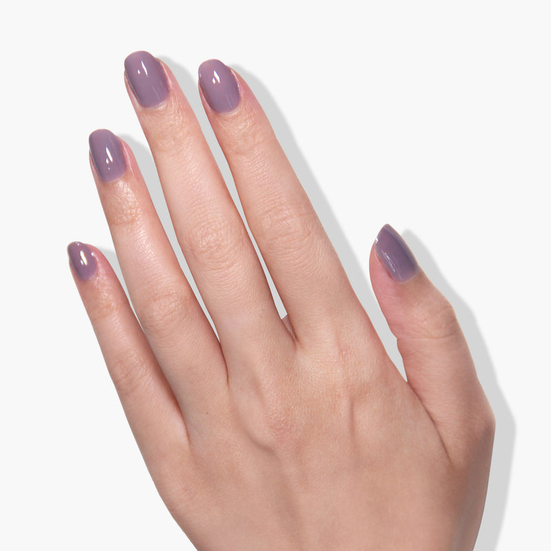 A hand with manicured nails, painted in LONDONTOWN's Cashmere—a luxurious plum nail polish with superior one-coat coverage—is shown against a white background.
