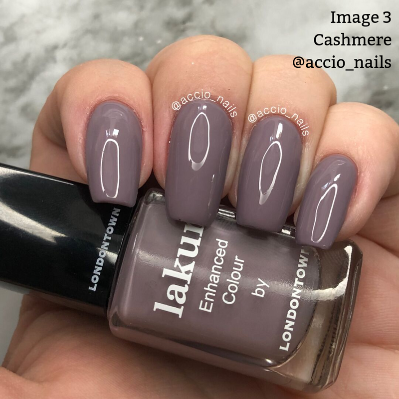 A hand with manicured nails painted in a vegan, cruelty-free plum color polish, holding a bottle of LONDONTOWN nail polish in the shade Cashmere. The image also displays the Instagram handle @accio_nails.