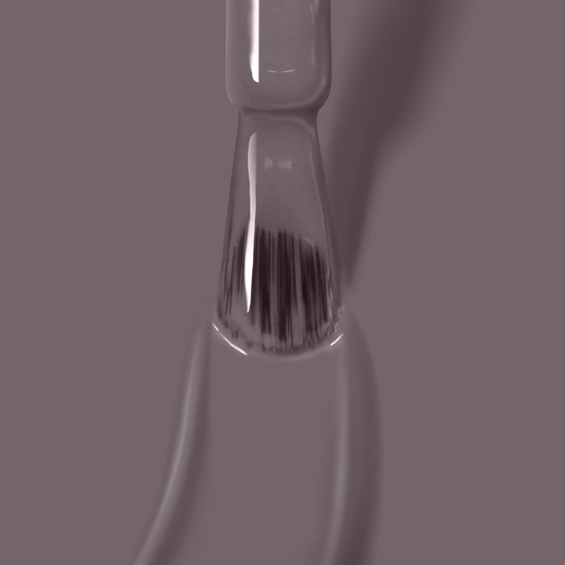 A close-up image of a nail polish brush applying LONDONTOWN's Cashmere, a vegan and cruelty-free grayish-purple polish, offering superior one coat coverage on a slightly blurred background.