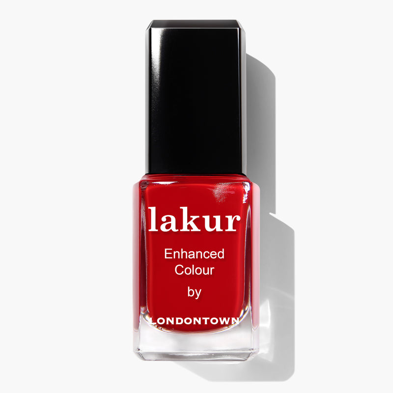 A bottle of deep red crème nail polish, named "Changing of the Guards" by LONDONTOWN, features a stylish black cap. The label reads "lakur Enhanced Colour by LONDONTOWN." This vegan and cruelty-free formula ensures your nails look stunning while being kind to the planet.