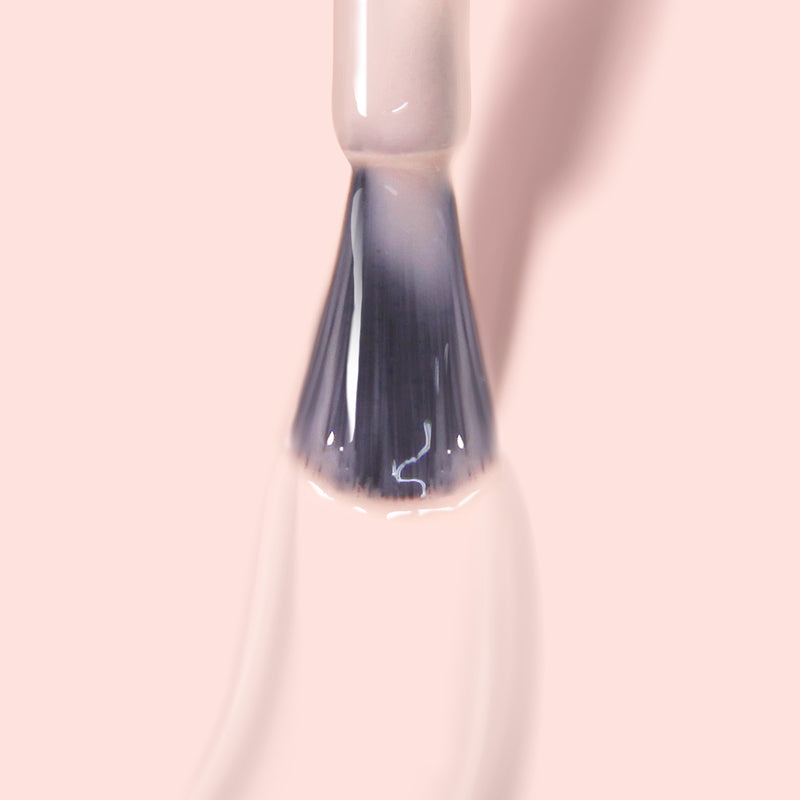 Close-up of a LONDONTOWN Cheerio nail polish brush applying a sheer neutral pink color on a smooth surface, perfect for achieving a delicate French manicure.