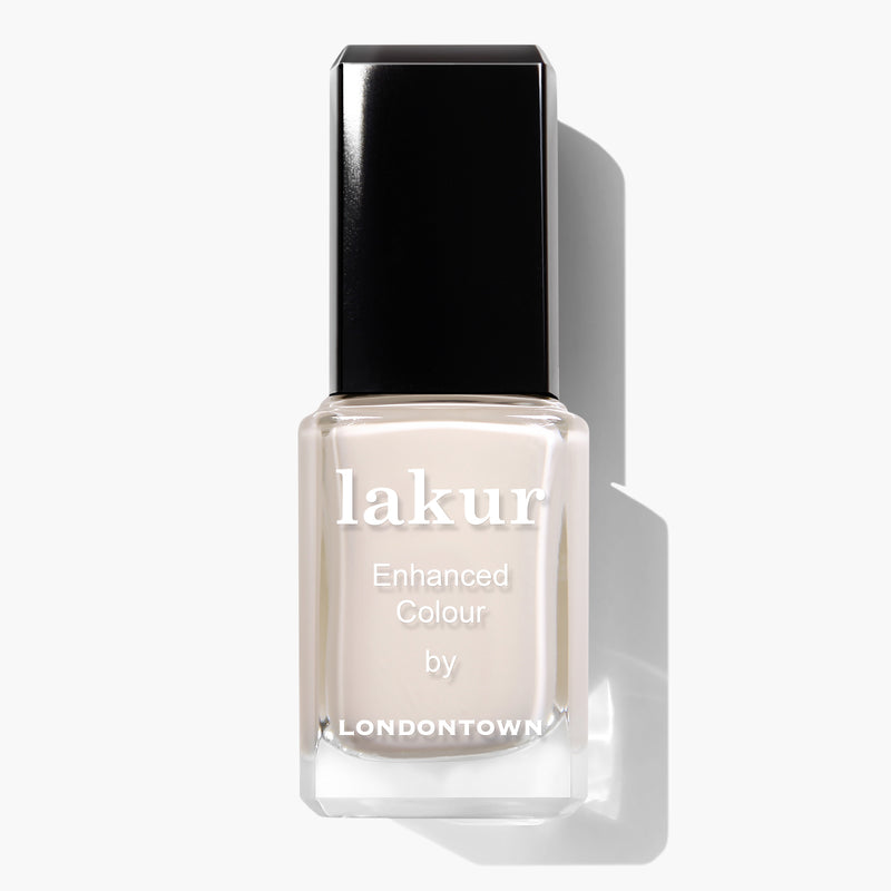 A bottle of LONDONTOWN Chelsea Porcelain nail polish features a smooth, glossy finish. The square-shaped bottle has a black cap and white text on the front, showcasing its milky off-white crème shade. This cruelty-free nail polish is perfect for those seeking a light, neutral color.