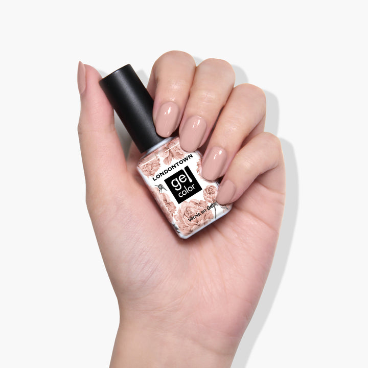 A hand with manicured nails holding a bottle of LONDONTOWN&