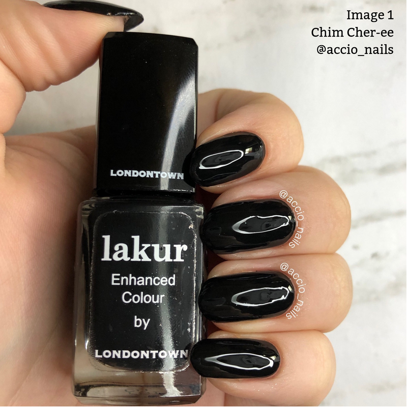 A hand with black polished nails holds a bottle of "Chim Cher-ee" jet black crème nail polish by LONDONTOWN, renowned for its vegan cruelty-free formula.