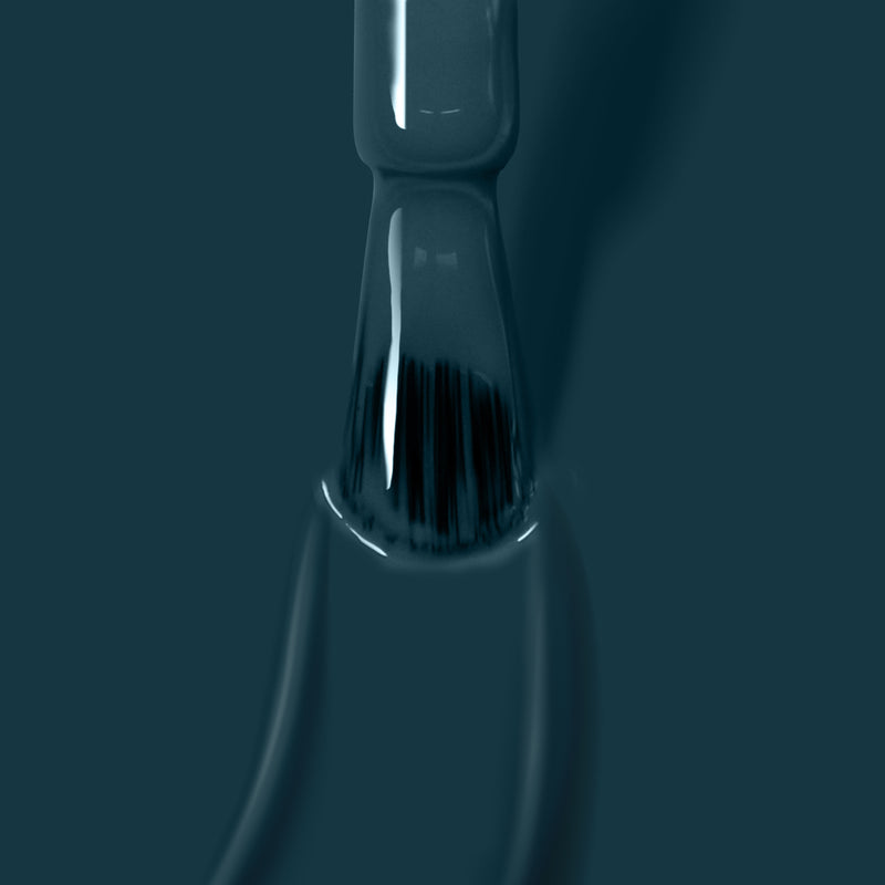 Close-up of a nail polish brush coated with LONDONTOWN's dark-colored, vegan nail polish "Chivvy Along," with the bristles partially visible against a dark green background.