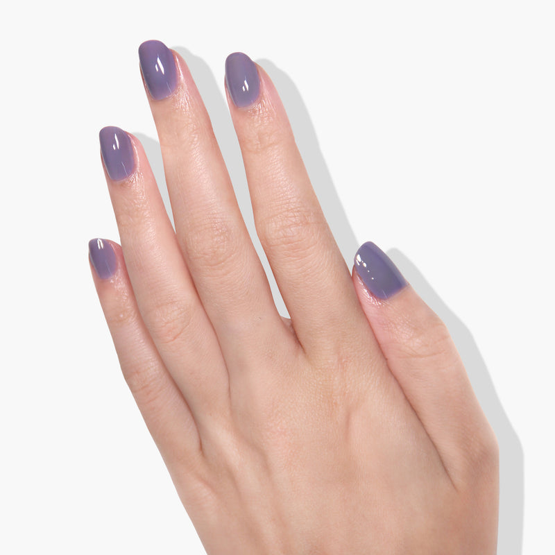 A hand with a Cozy Cashmere gel manicure by LONDONTOWN in a purple crème shade on a white background.
