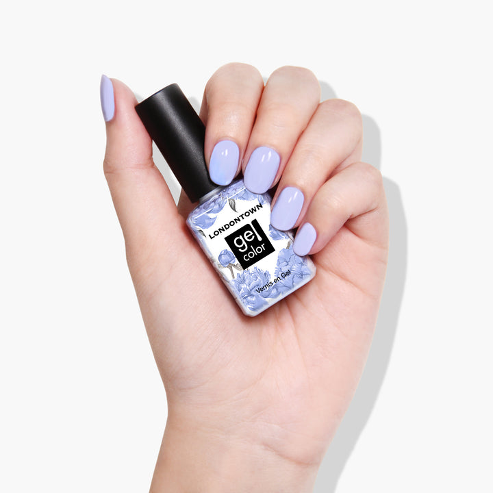 A hand with light purple nail polish holds a bottle of LONDONTOWN&