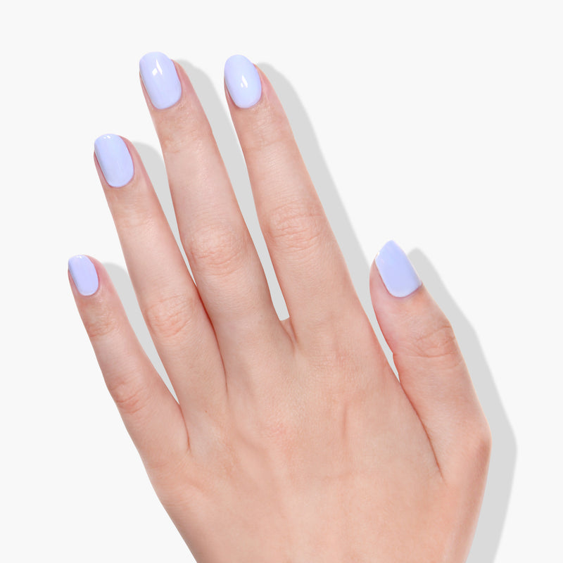 A hand with short, neatly manicured nails painted in LONDONTOWN's Dainty Daze, a periwinkle blue creme, displayed against a plain white background.
