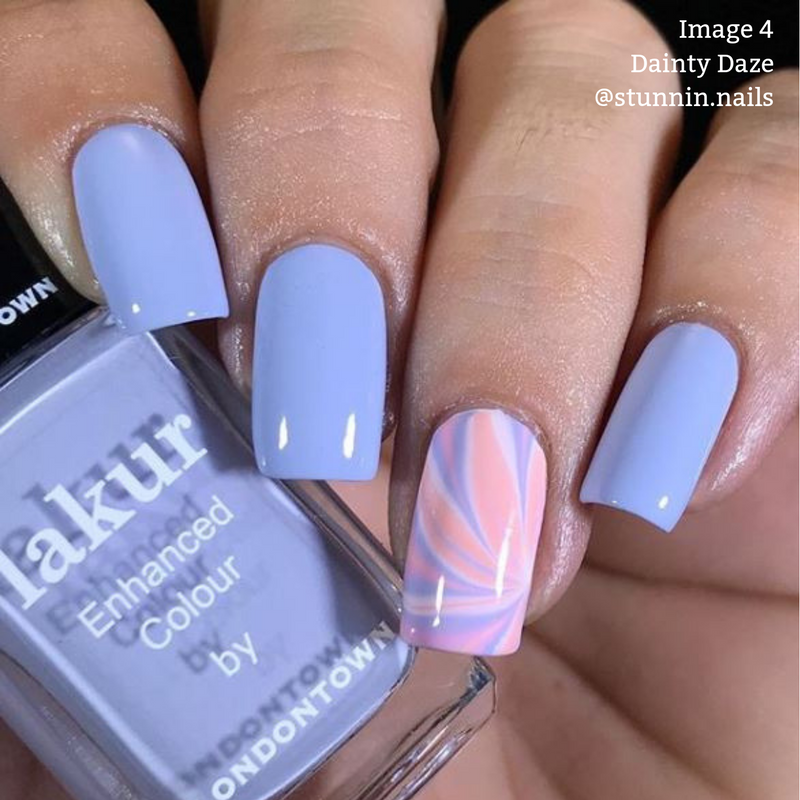 Four lavender nails accompanied by one accent nail showcasing a pink and white marbled pattern; a vegan, cruelty-free nail polish bottle labeled “nailkure Enhanced Colour by LONDONTOWN” is held near the nails. Text overlay: “Image 4 Dainty Daze @stunnin.nails”.