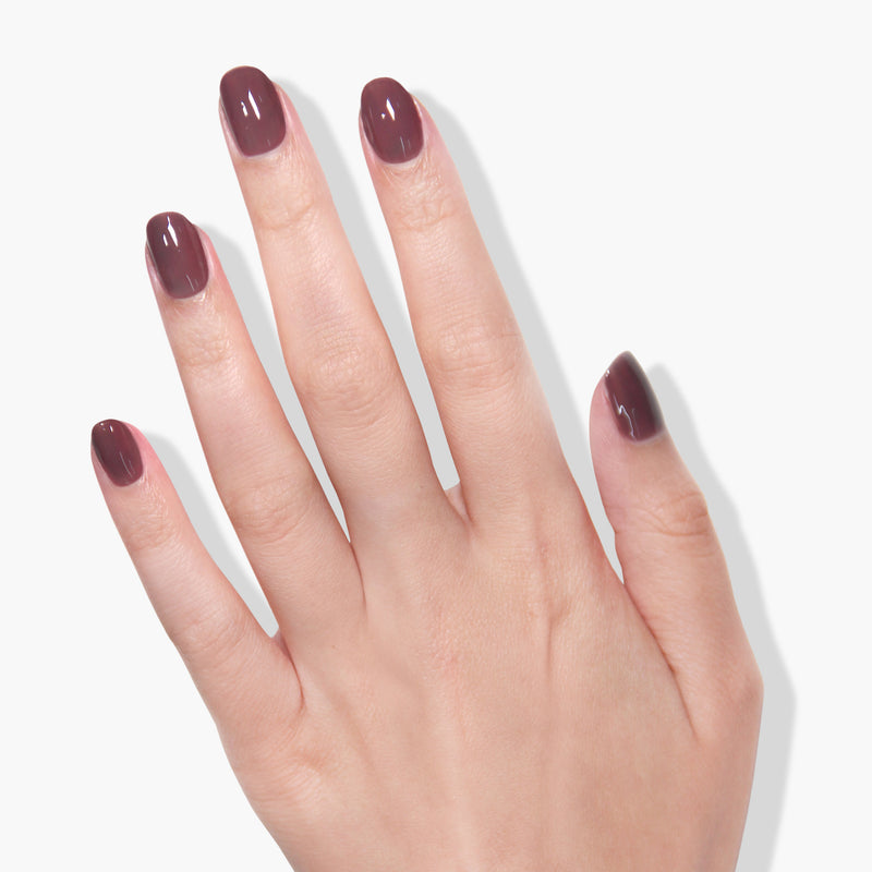 A hand with short, neatly trimmed nails painted in the stunning shade of Darjeeling by LONDONTOWN, illuminated under a UV/LED light against a white background.