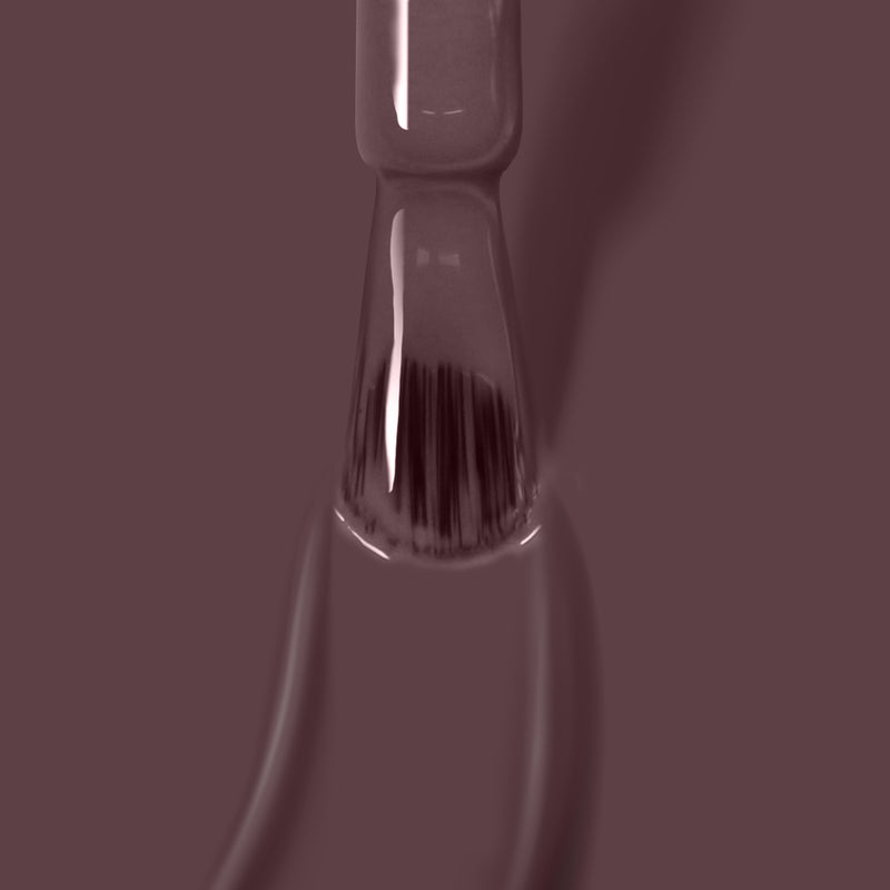 Close-up of a nail polish brush with LONDONTOWN's Darjeeling gel manicure coating the bristles, against a solid brown background.