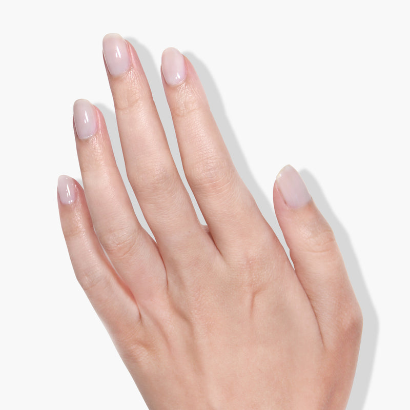 The image shows a close-up of a left hand with short, neatly manicured nails featuring LONDONTOWN's Doilies, a light, natural polish obtained from a gel manicure. The sheer white finish is flawless against the plain white background.