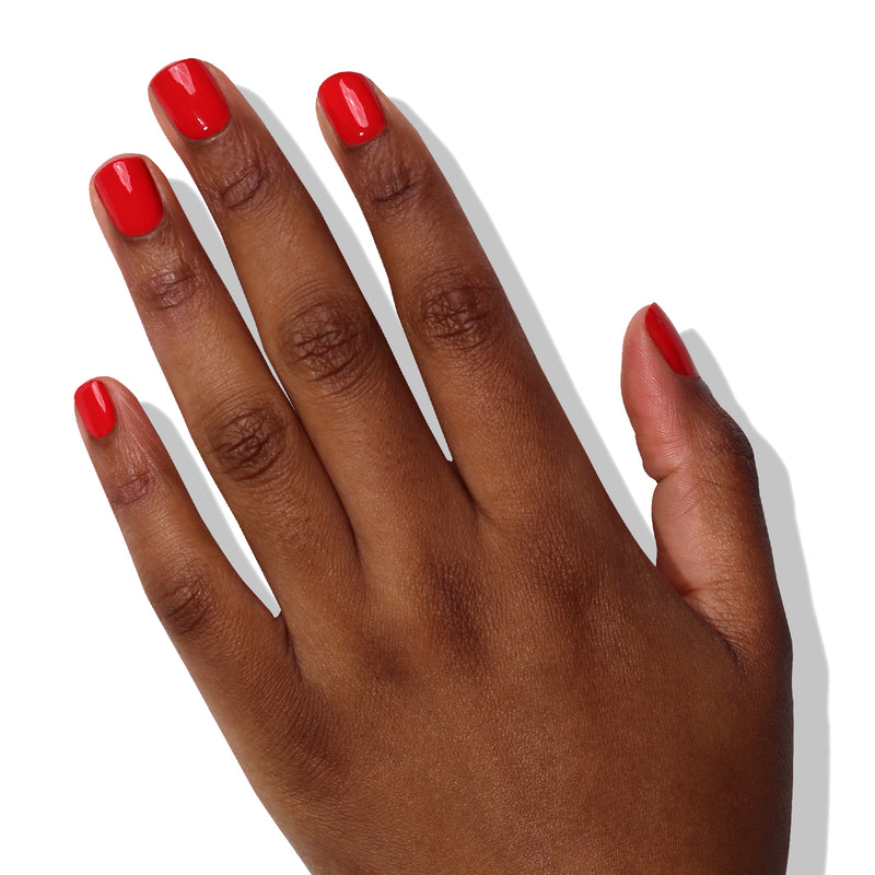 A hand with brown skin and neatly manicured nails painted in LONDONTOWN's Down to Dilly, a hot pink crème nail polish, shown against a plain white background.