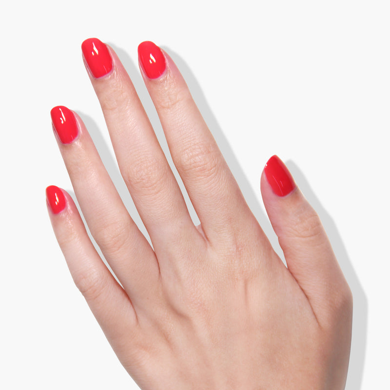 A hand with neatly manicured nails painted in the stunning LONDONTOWN Down to Dilly hot pink crème gel color shines brilliantly against a white background.