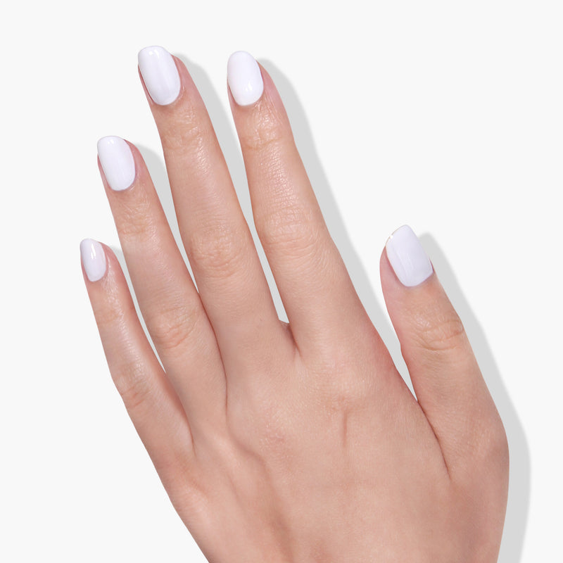A hand with a light skin tone shows off a French manicure with dazzling pure crème white Duchess nail polish by LONDONTOWN against a pristine white background.