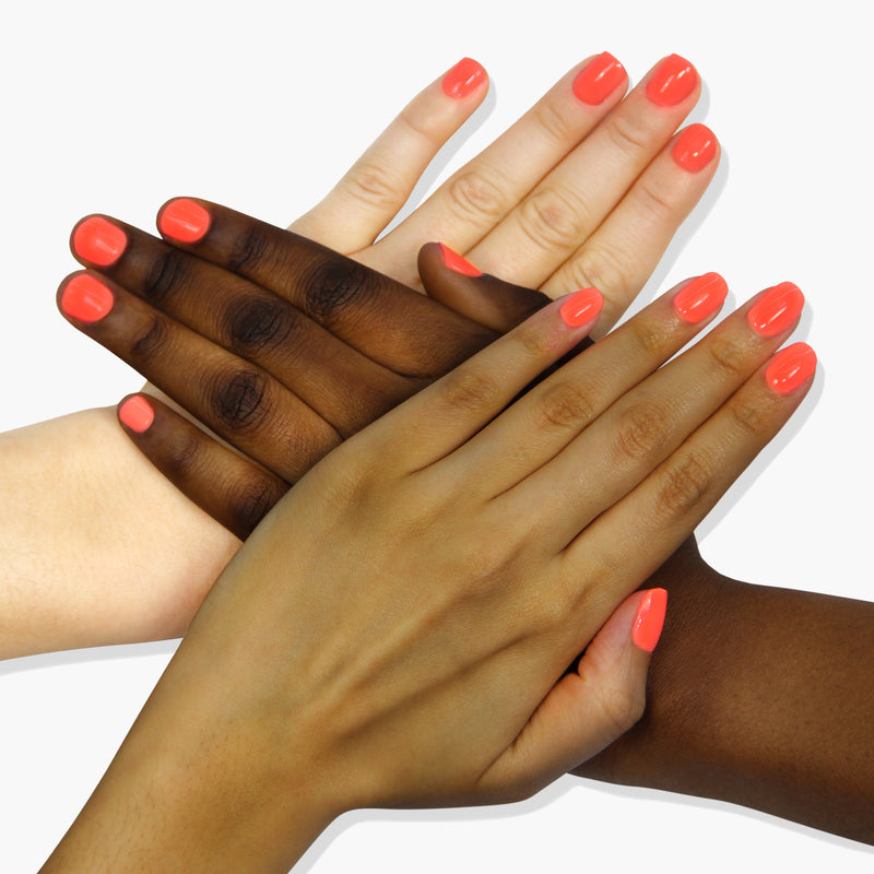 Four hands of different skin tones wearing LONDONTOWN’s Flashback, a vibrant radiant sunset orange nail polish, are gracefully placed over one another on a white background.