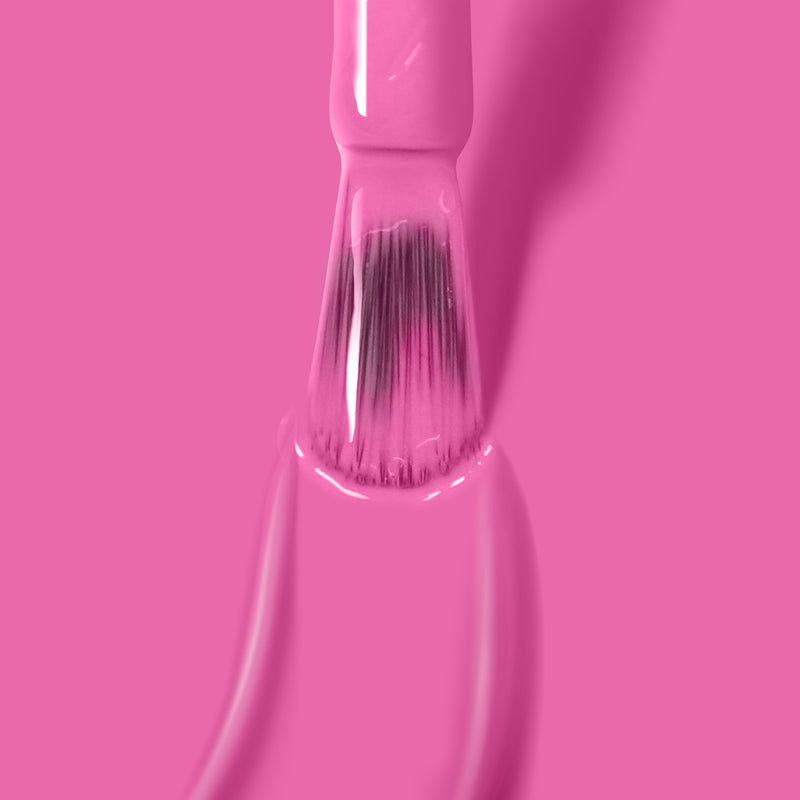 A paintbrush is dipped in bright pink paint against a solid pink background, reminiscent of LONDONTOWN's vibrant Fruit Tella polish.