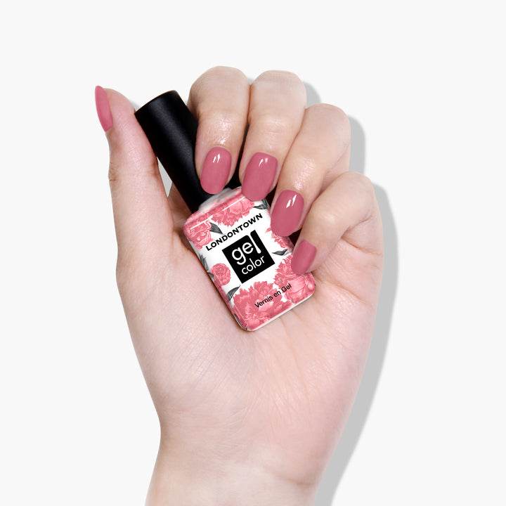 A hand with neatly manicured clay rose nails holds a bottle of LONDONTOWN&