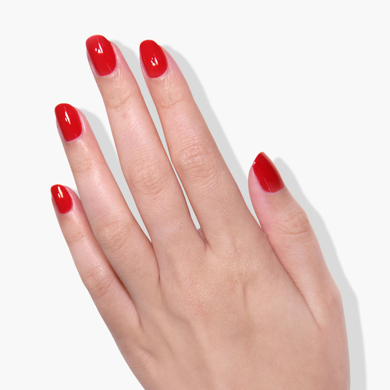 A hand with manicured nails painted in LONDONTOWN's Changing of the Guards, a deep red crème reminiscent of Buckingham Palace's elegance. The fingers are slightly spread, and the background is plain white.