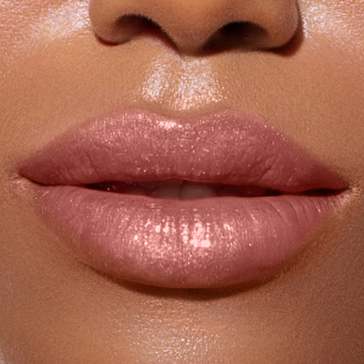 Close-up image of glossy, peachy nude lips slightly parted, accentuated with LONDONTOWN's Plush Shine Lip Gloss in Gossamer.