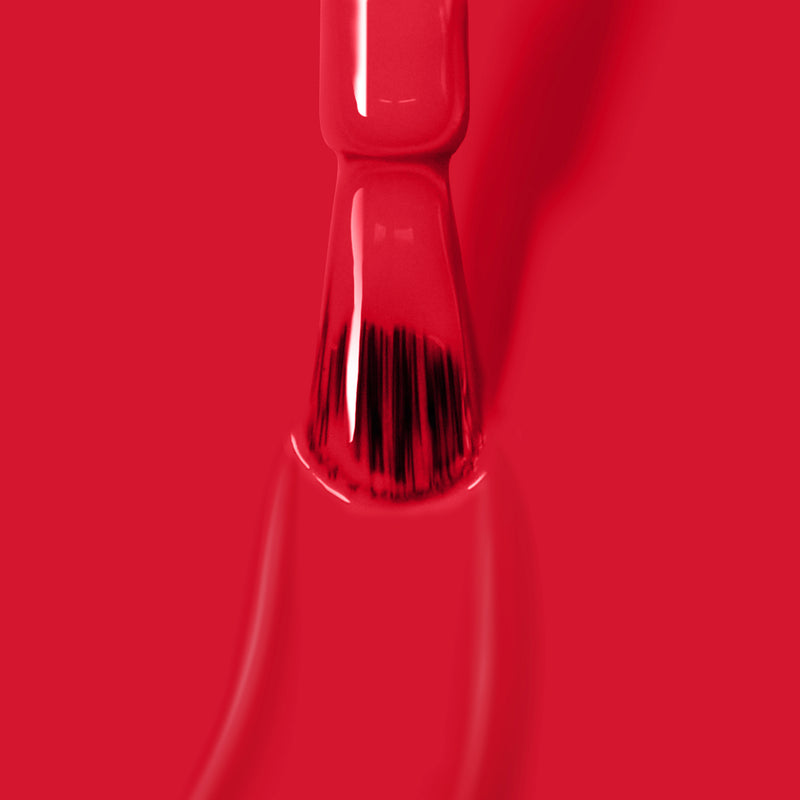 A close-up of the LONDONTOWN Guilty Pleasure vegan paintbrush applying bright red, cruelty-free paint on a smooth surface.