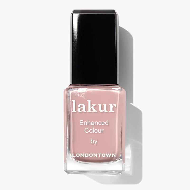 A bottle of LONDONTOWN Lakur Enhanced Colour nail polish in the shade Honeymoon, featuring a soft pink color, with a black rectangular cap and reflective surface. This vegan and cruelty-free formula ensures your nails look stunning while being kind to animals.