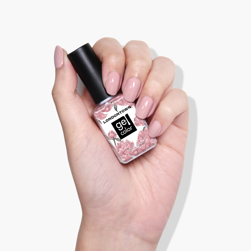 A hand with manicured nails holds a bottle of LONDONTOWN vegan nail polish gel color, "Honeymoon," featuring a floral design on the label.