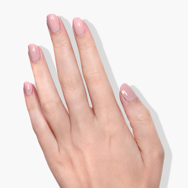 A hand with neatly manicured nails painted in "Honeymoon" light pink nail polish by LONDONTOWN, shown against a white background.