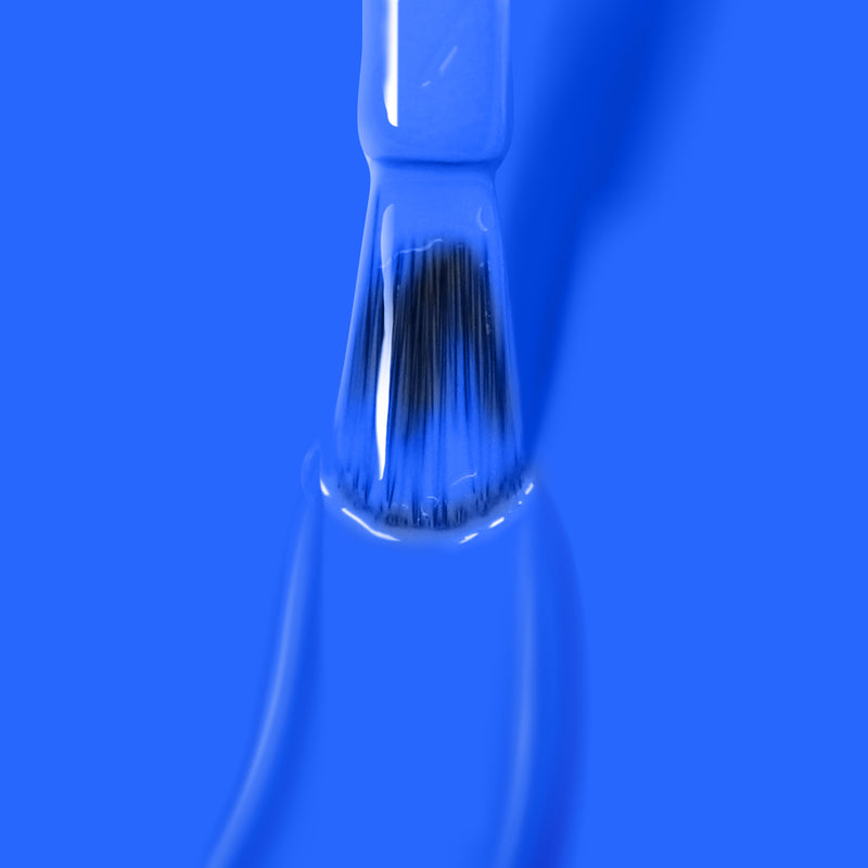 A paintbrush dipped in Iconic electric blue nail polish by LONDONTOWN against a blue background, reminiscent of the 2019 Allure Best of Beauty Award-winning vegan, cruelty-free products.