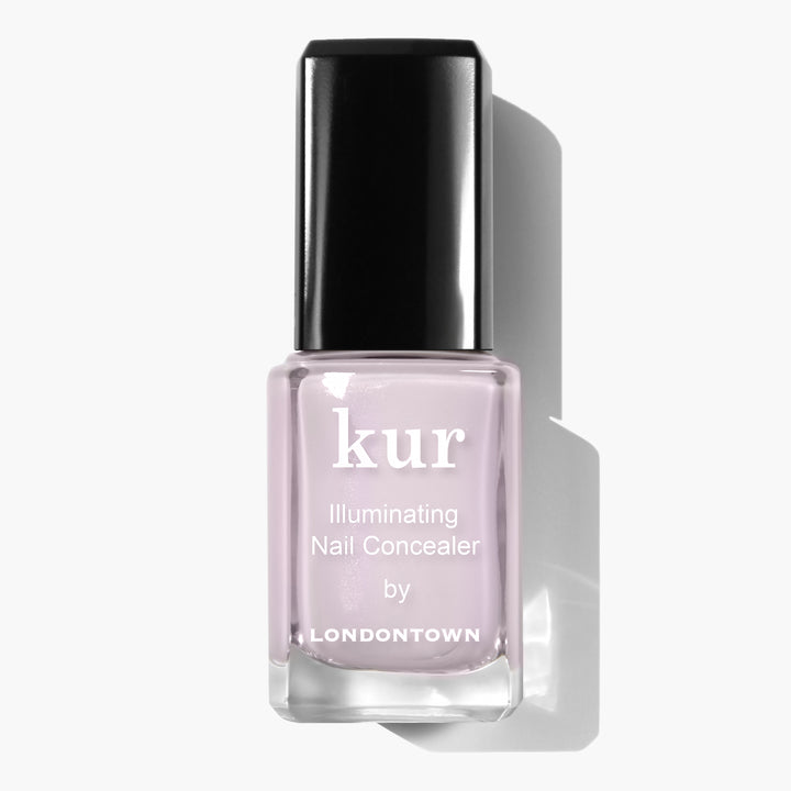 A bottle of LONDONTOWN Pink Illuminating Nail Concealer with a black cap on a white background, offering an instant illuminating brightener with a subtle milky finish.