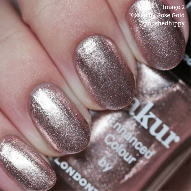 Close-up of a hand with nails painted in a sparkly, metallic rose gold color, holding a bottle of cruelty-free LONDONTOWN nail polish marked "Kissed by Rose Gold.