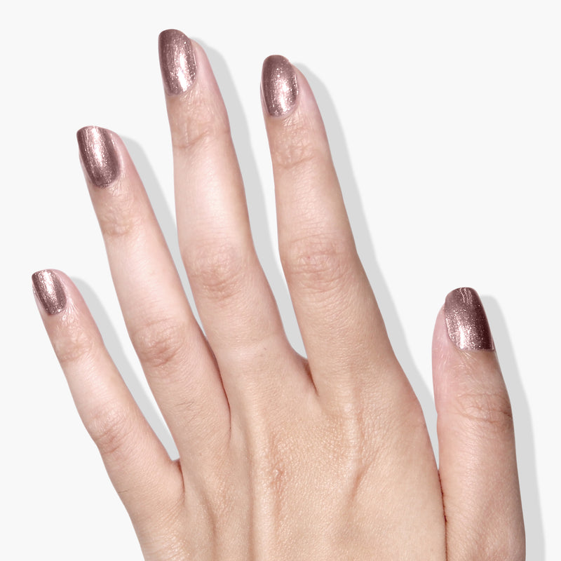 A hand with LONDONTOWN's Kissed by Rose Gold nail polish on all five fingernails, shown against a plain white background.