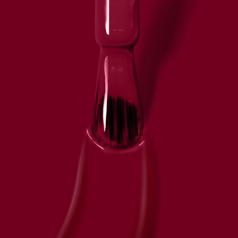 A close-up image of a nail polish brush dipped in the rich, dark red, vegan gel color "Lady Luck" by LONDONTOWN.